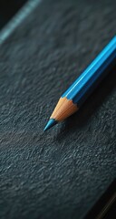 Close-up of a vibrant blue colored pencil on a dark textured surface