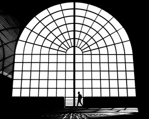 A big backlit window and the silhuette of a man walking