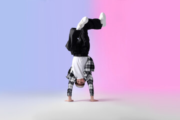 Boy in stylish clothes dancing on color background