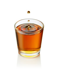 Golden drop splashing into glass whisky or tequila, creating mesmerizing concentric ripples against pristine white background
