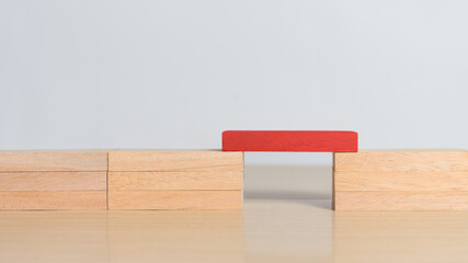 Red wooden block connecting both sides.  Concept of problem solving, leadership, key contribution, and standing out by enabling connection and progress.