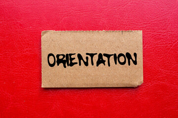 Orientation message written on ripped torn cardboard paper piece on red background. Conceptual orientation symbol. Copy space.