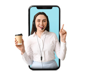 Female technical support agent in headset with paper cup of coffee pointing at something on blue...