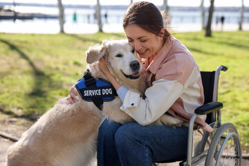Woman in wheelchair hugging her service dog at park