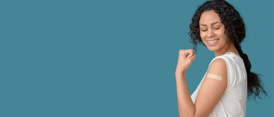Young African-American woman with applied medical patch after vaccination on blue background