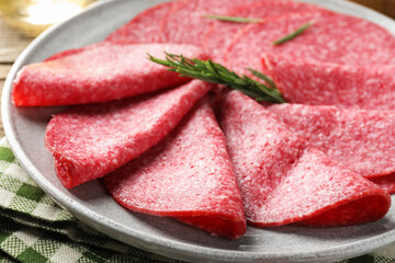 Slices of delicious sausage with rosemary served on table, closeup