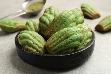 Tasty madeleine cakes and matcha powder on light table, closeup