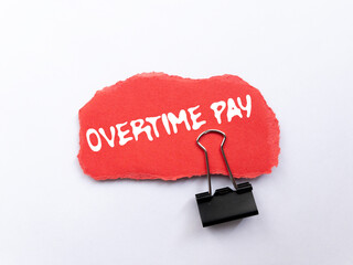 Overtime pay message written on ripped torn red paper piece on white background. Conceptual...