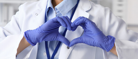 Female doctor making heart gesture in clinic, closeup