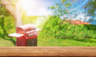summer time in backyard garden with grill BBQ, wooden table, blurred background