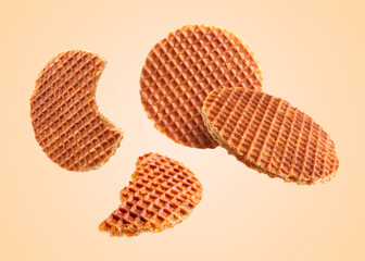 Yummy Dutch waffles (stroopwafels) flying on beige background