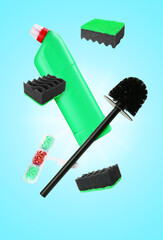Toilet brush and other cleaning supplies in air on light blue background