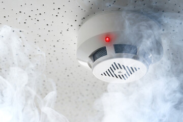 Fire alarm system. Detector on ceiling triggered by smoke