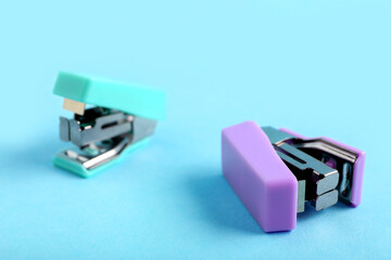 Fototapeta premium Different small staplers on blue background