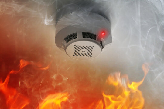 Fire alarm system detector on ceiling triggered by smoke and flame