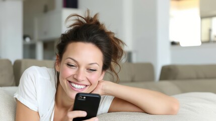Relaxed woman reclining on comfortable sofa, browsing smartphone with warm smile, enjoying digital connection and peaceful home atmosphere