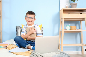 Cute little boy with book studying in bedroom