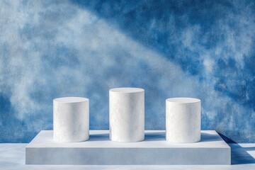 Three white cylindrical podiums on a light-blue platform against a textured blue backdrop