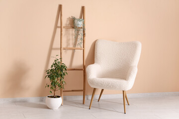 White armchair, ladder and houseplants near beige wall in room
