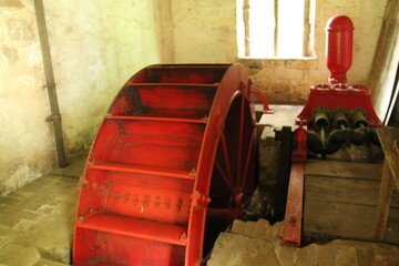 An Old Metal Water Wheel in a Stone Built Pump House.