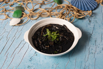 Squid in rich black ink sauce garnished with fresh parsley.