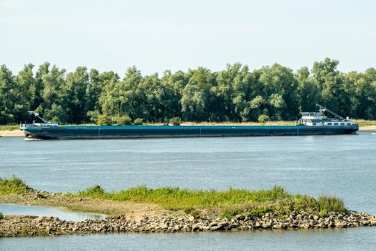 Gorinchem, netherlands, river merwede, CTT HENGELO, long barge sailing on wide river near green shore