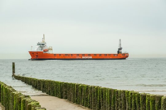 Disheok, Zeeland, Netherlands, North Sea, LADY MONIQUE, Cargo ship sailing near wooden breakwaters on cloudy day