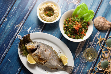 Lebanese seafood and mezza spread styled over rustic blue table.