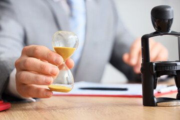 Businessman with hourglass at table in office, closeup