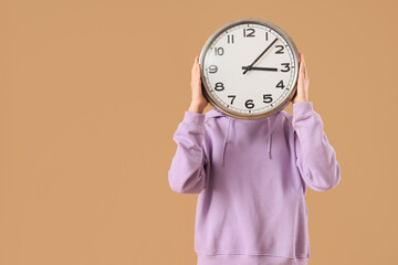 Woman with clock on beige background
