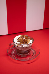 Layered chocolate dessert served in glass cup over red stripes.