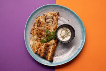 Grilled flatbread slices served with creamy yogurt dip and herbs.