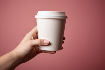A person holds a cup of coffee against a bright pink background, perfect for everyday use or as a creative concept