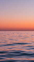 Obraz premium Serene Sunset Ocean Waves Calm Sea at Dusk Pink and Orange Sky