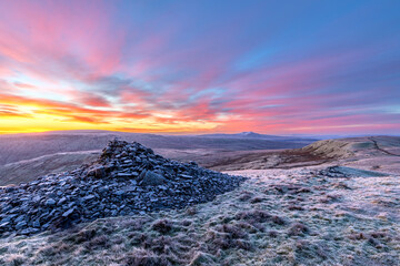 Great Coum summit cairn in the Yorkshire Dales UK on a frosty Winter morning with Ingleborough in the distance covered in snow. 