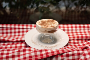Classic tiramisu dessert in a glass dish on plate.