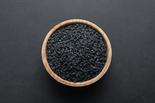 Aromatic black caraway in bowl on dark table, top view