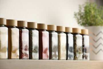 Different aromatic spices in jars on wooden shelf indoors, closeup