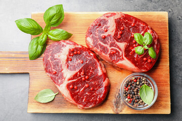 Pieces of raw beef meat and spices on gray table, top view