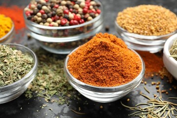 Different aromatic spices in bowls on dark table, closeup