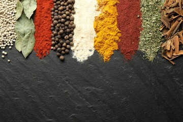 Many different spices on black table, flat lay. Space for text