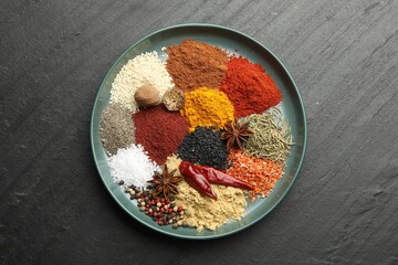 Different aromatic spices on dark textured background, top view