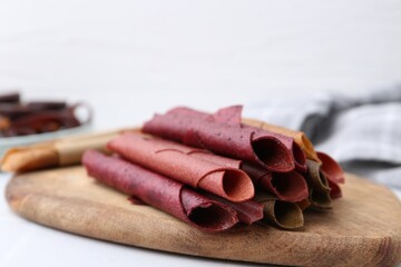 Tasty fruit leather rolls on white table, closeup. Space for text