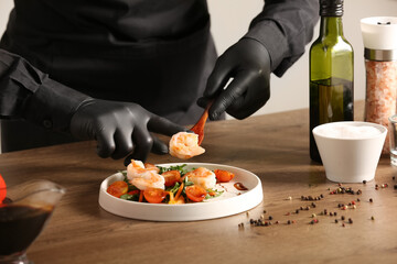 Male chef cooking shrimps with vegetables at table in kitchen, closeup