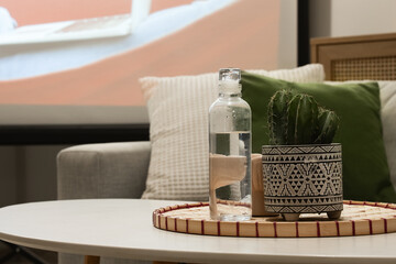 Cactus and bottle of water on coffee table in stylish living room with projector screen