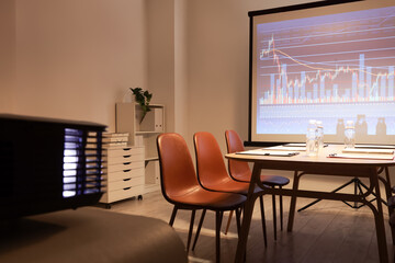 Interior of modern conference hall with table, chairs and projector screen