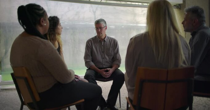 Middle aged man opens up with raw emotional testimony during intense therapy session, support group listens in silence as he reveals deep personal pain in safe space