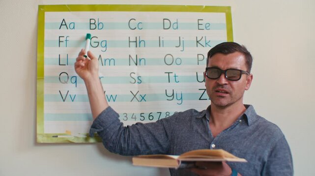 European Caucasian white male man English teacher tutor in glasses teaches English alphabet