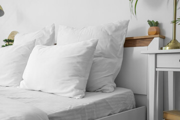 Soft white pillows on bed in light room