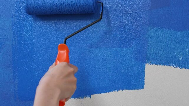 Roller Brush Painting, Worker painting on surface wall Painting apartment, renovating with blue color paint. Leave empty copy space white to write descriptive text beside.